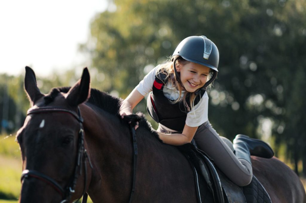 Kind rijdt op paard en glimlacht breed